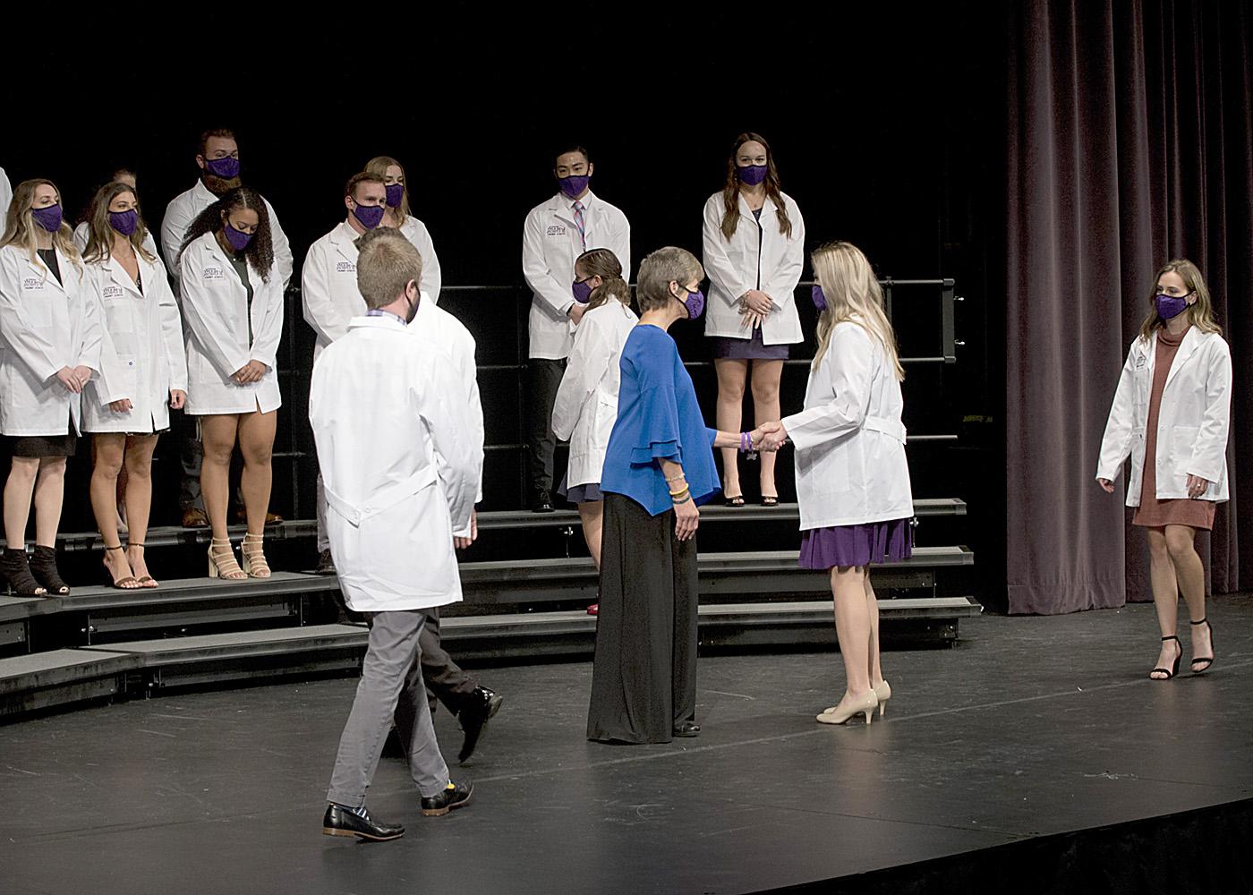 Students walking across the stage at Mount Union's PT White Coat ceremony